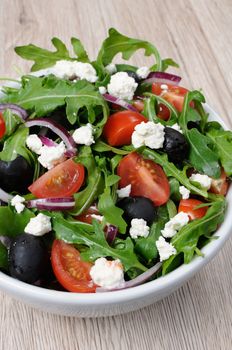 Variation of Greek salad with arugula, cherry slices, feta and olives
