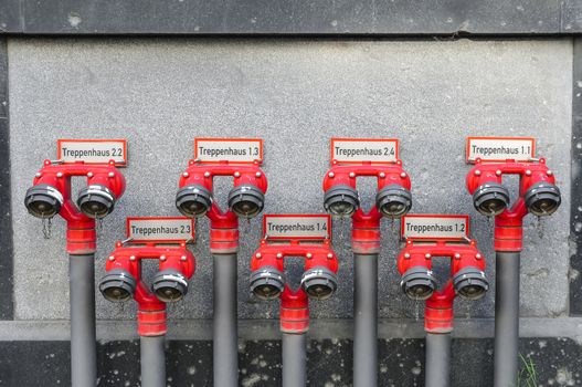 A row of red hydrants labeled wit staircase numbers