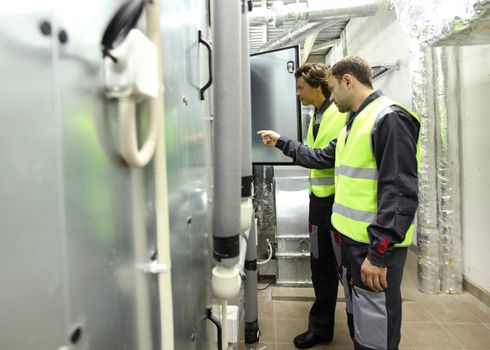 Workers in electrical switchgear room of CNC plant