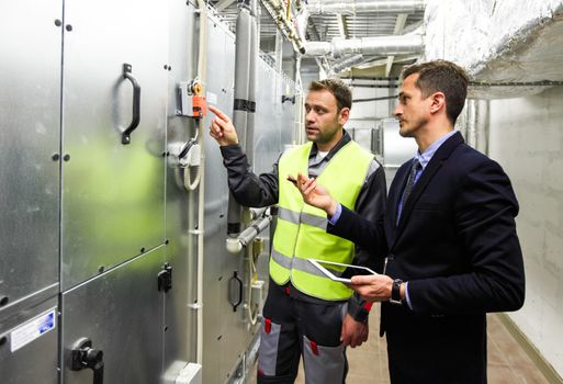 Worker and manager in electrical switchgear room of CNC plant