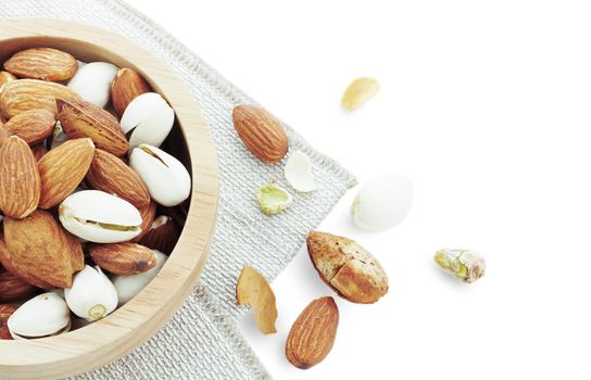 Assorted almonds in a bowl on white background.