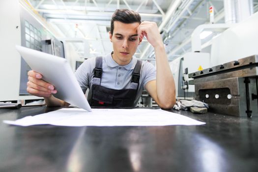 Man working with documents at plant near CNC machines