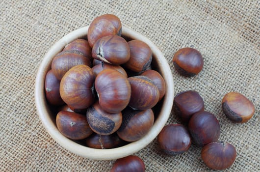 Chestnuts in a bowl on sackcloth.