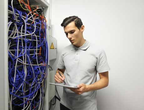 Young engeneer man in network server room with digital tablet