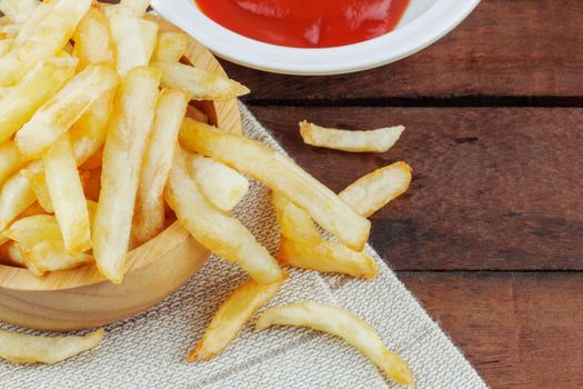French fries and tomato sauce on wooden floor.