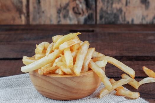 French fries in a bowl on wooden floor.