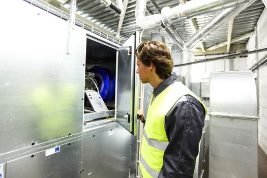 Worker in electrical switchgear room of CNC plant