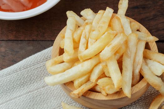 French fries in a bowl and sauce on wooden.