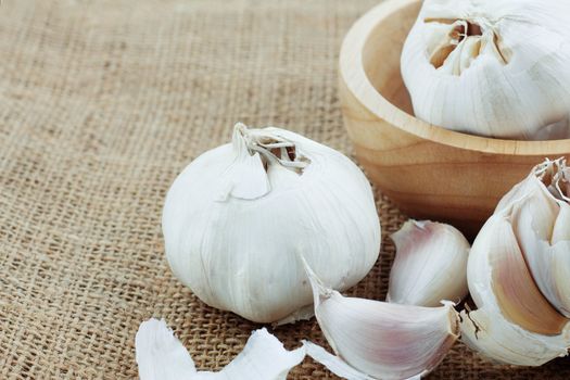 Garlic on sackcloth and wooden bowl.