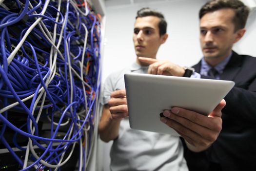 Young engeneer and manager in network server room with digital tablet