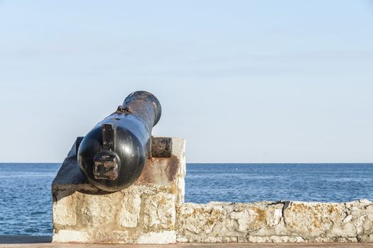 Ancient old cannon on coastal fortress walls aiming to the sea; fortress defense