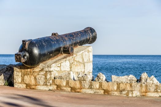 Ancient old cannon on coastal fortress walls aiming to the sea; fortress defense