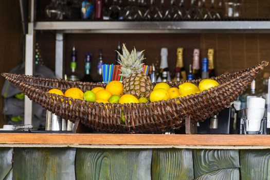 Bar counter with fruits in basket and shelfs with bottles in background