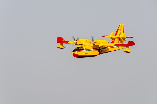 Yellow and red Canadair water bomber, turbo prop firefighting aircraft in action