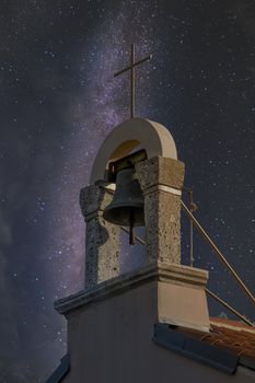 Church bell tower with cross under the milky way