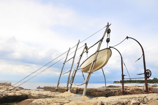 Traditional hoisting of boats ashore in northern Adriatic sea, a small fisher boat hoisted out of the water