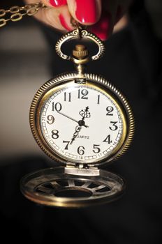 Old watch held by a girl with red fingernails