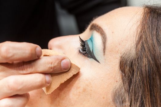 Makeup artist applying foundation using a sponge to a white woman