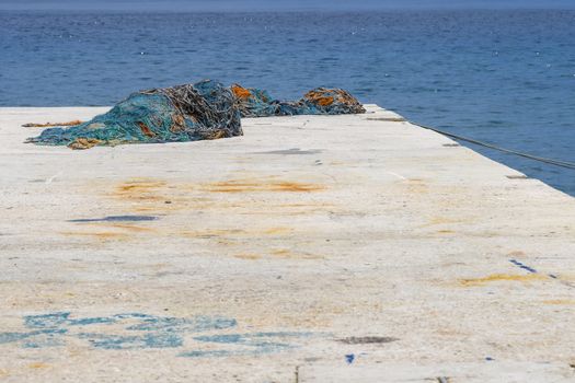 Concrete pier with blue and brown fishing nets lying around