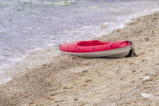 Red and white plastic canoe on sandy beach, copyspace, nobody