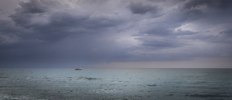 Sailboat in open sea and astorm approaching, dramatic skies, calm sea
