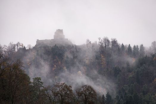 Mysterious Smlednik castle ruins on top of a hill, engulfed in late autumn fog