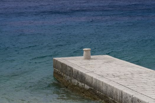 Traditional stone pier and blue sea in backgound