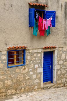 Laundry driying in sun, washing line hanging from blue windows and blinds.