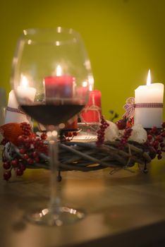 Christmas / Advent decoration with four lit candles, selective focus, glass of red wine in front