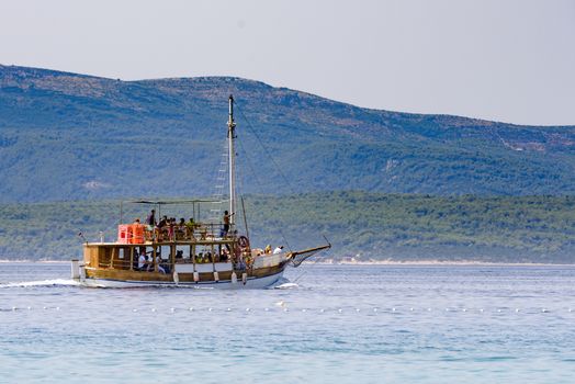 Tourist boat with guests on sightseeing tour between mediterranean island in Adriatic sea, Dalmatia, Croatia