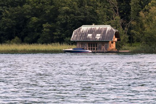 Traditional wooden house on lake with outdoor patio and boat