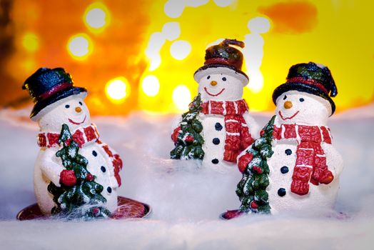 Three smiling snowmen in snow, Happy New Year 2017, Christmas, bright defocused lights in background
