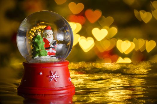 Christmas snow globe with xmas lights in background; Santa Claus with Cristmas tree; heart shapes, bokeh blur