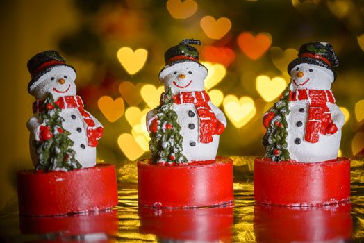 Three Christmas snowmen and heart shaped lights in background, heart shaped bokeh blur, Christmas decoration