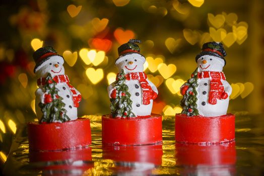 Three Christmas snowmen and heart shaped lights in background, heart shaped bokeh blur, Christmas decoration