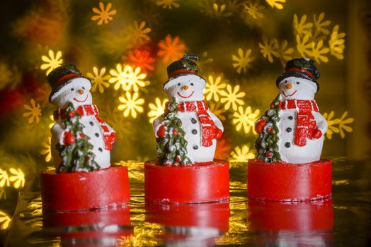 Three Christmas snowmen and heart shaped lights in background, flower shaped bokeh blur, Christmas decoration