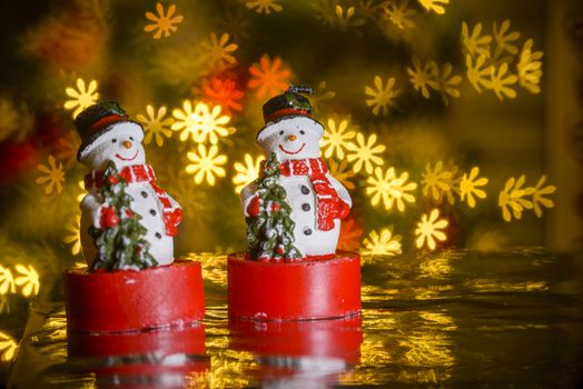 Two Christmas snowmen and flower shaped lights in background, flower shaped bokeh blur, Christmas decoration