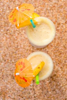 top view two glasses with pineapple cocktail on a sandy beach close-up