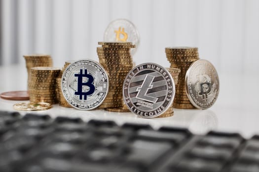 Digital currency physical silver bitcoin coin and silver litecoin near money and black computer keyboard.