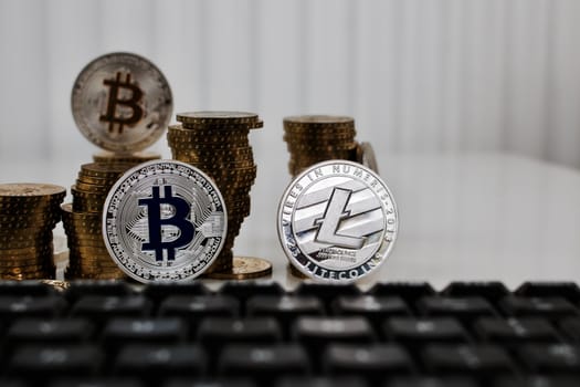 Digital currency physical silver bitcoin coin and litecoin near black keyboard.