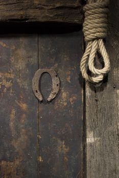 Rusty horseshoe and rope on an old wooden door