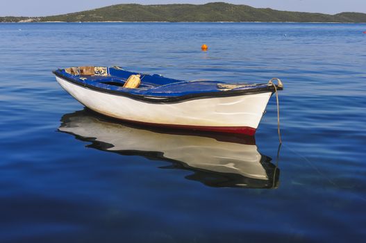 Small fishing boat reflecting in the water, island in background