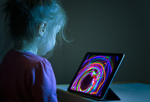 Litlle girl watching tablet PC colorful screen