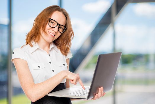 Happy businesswoman presses a button on the laptop in the office