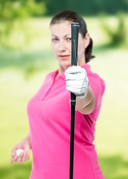 athlete shows a golf club at the camera on a background of golf courses