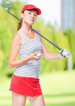 Slender sportswoman golfer with stick and ball on a background of golf courses