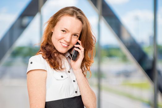 Charming secretary with a phone in his hand in the office