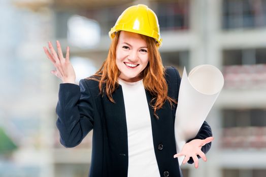 Women chief architect with drawings in a yellow helmet at a construction site