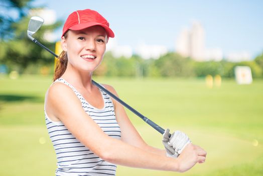 Golfer putting golf stick on shoulder while smiling on a background of golf courses