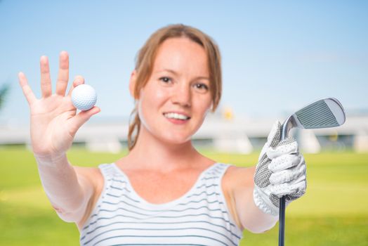 Smiling girl shows a camera in the ball and a golf club on a white background